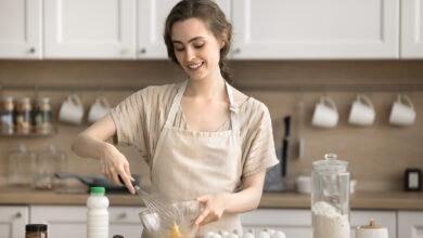 Woman in apron holds a whisk and beats eggs, preparing pancakes. The trad-wife trend is up for debate for Year 9 students.