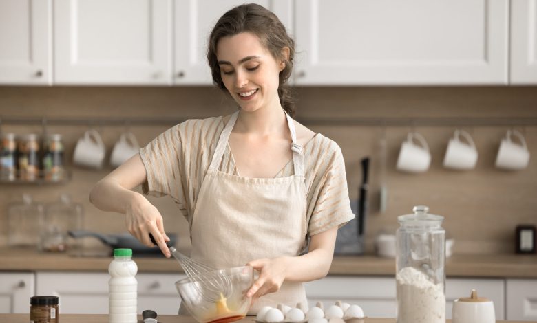 Woman in apron holds a whisk and beats eggs, preparing pancakes. The trad-wife trend is up for debate for Year 9 students.