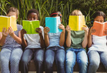 Children reading books at park.
