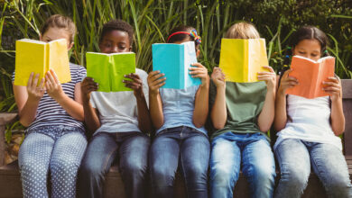 Children reading books at park.