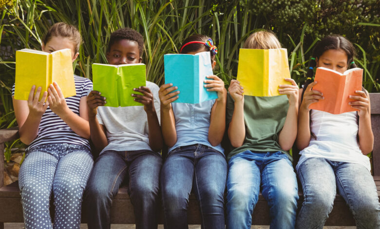 Children reading books at park.