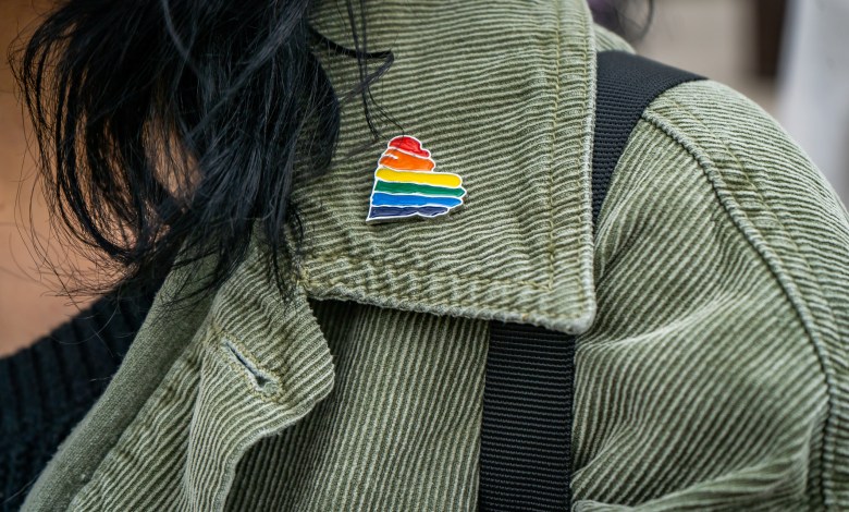 green jacket collar close up of a rainbow heart gay queer pin