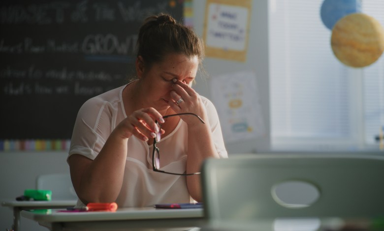 Tired Female Teacher Sitting Alone at the Desk in Empty Classroom, Relaxing After Class. Woman Feeling Stress, Burnout and Mental Exhaustion in Educational Environment, Working in Elementary School.